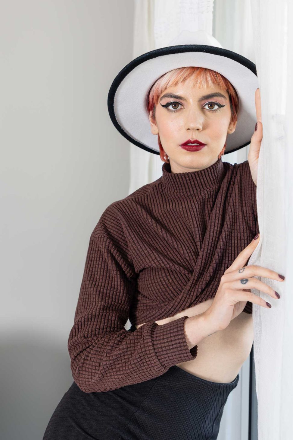 Portrait en couleur de Rossana avec un chapeau en feutre et un pull marron